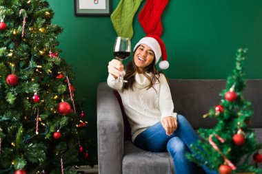 Şerefe! Neşeli İspanyol kadın bir kadeh şarapla kadeh kaldırıyor ve Noel 'i evde kutluyor.