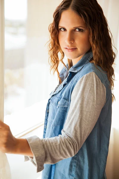 Young woman standing near window — Stock Photo, Image