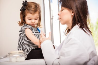 Pediatrician giving a girl a shot clipart