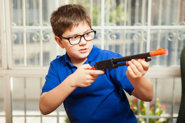 Мальчик играет с игрушечной винтовкой — стоковое фото