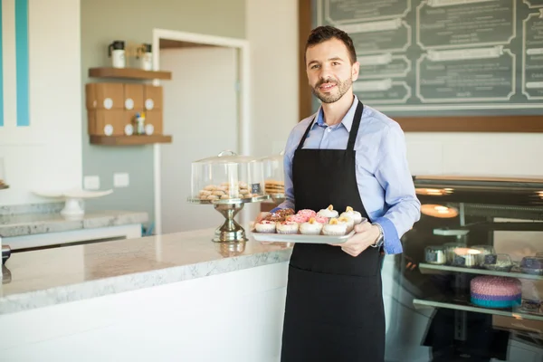 Ägaren håller en bricka med cupcakes — Stockfoto