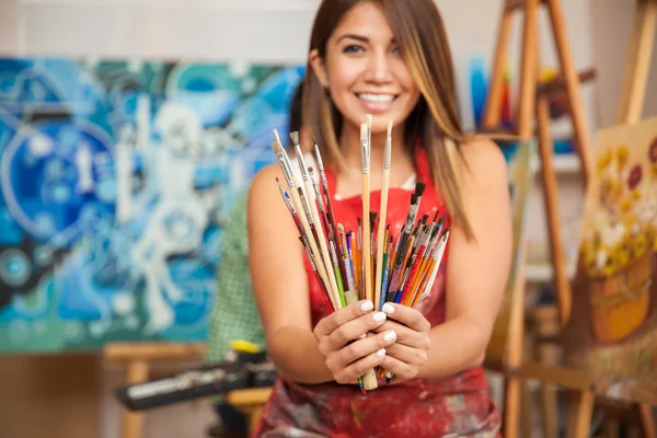 Woman holding a bunch of paintbrushes — Stock Photo, Image