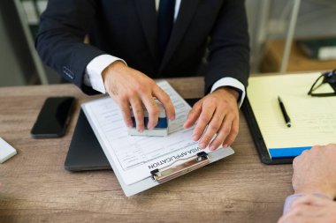 Resmi kişi, göçmenlik ve onay sürecini simgeleyen vize başvuru formunu ahşap masaya damgaladı.