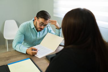 Endişeli adam hukuk uzmanına danışıyor, önemli evrakları okuyor ve ofis ortamında danışmanlık yapıyor.