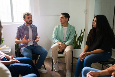 Umutlu insanlar bir çemberde oturuyor, deneyimlerini paylaşıyor ve zihinsel sağlık grubu oturumunda destek öneriyorlar.