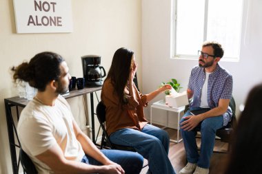 Destek grubunda üzgün duyguları tartışan ağlayan bir kadın. Toplum ve zihinsel sağlık danışmanlığı yoluyla yardım alan insanlar. Yalnız değil.