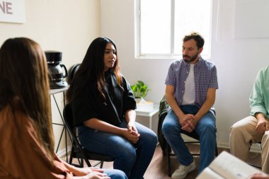 Bir çemberde oturan insanlar, zihinsel sağlık, iyileşme ve bağımlılık sorunları hakkında konuşuyor ve dinliyorlar.