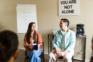 Grup terapisine katılan, tecrübelerini paylaşan ve güvenli bir toplum ortamında destek sunan insanlar