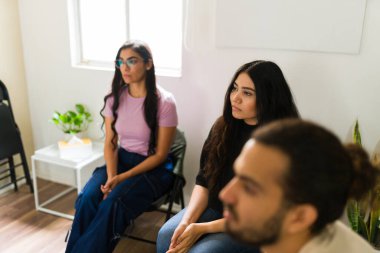 Destek grubu toplantısına katılan genç yetişkinler, akıl sağlığı ve refahla ilgili bir tartışmayı dikkatle dinliyor