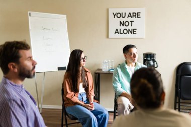Yetişkinler bir çemberde oturuyor, zihinsel refah için grup terapisi sırasında destek alıyor ve deneyimlerini paylaşıyorlar.