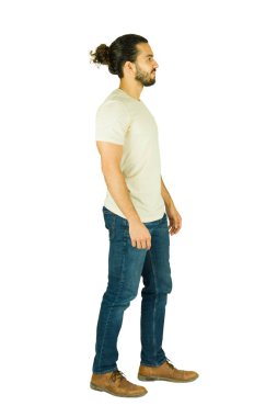 Uzun saçlı, topuz ve sakallı Latin bir adam, temiz beyaz bir stüdyo arka planında yan duruyor.