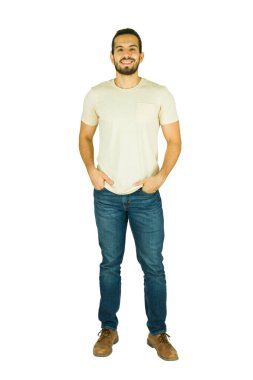 Sıradan kıyafetlerle ayakta duran mutlu bir adamın portresi, kameraya bakıyor ve beyaz arka planda gülümsüyor.