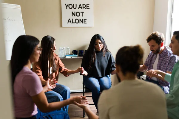Bir grup insan bir çemberde oturuyor, el ele tutuşuyorlar ve terapi sırasında duygusal destek alıyorlar.