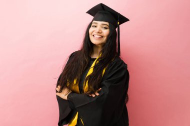 Mezuniyet şapkası ve cübbesi takan, kendine güvenen, akademik başarıyı ve başarıyı kutlayan sevimli bayan öğrenci.