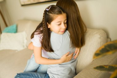 Sevgi dolu anne ve kız evlerinde kucaklaşıyorlar. Ebeveynler ve çocuklar arasındaki aile sevgisi, rahatlık ve güven