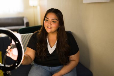 Genç mutlu içerik yaratıcısı, halka ışığı kullanarak sosyal medya takipçilerine video blogunu canlı yayında canlı yayınlarken özgüvenle gülümsüyor.