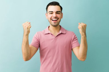 Neşeli adam başarıyı neşeli bir ifadeyle kutluyor ve yumruklarını kaldırıyor, mutluluğu, zaferi ve başarıyı hissediyor.