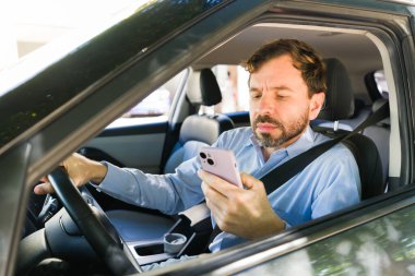 Erkek sürücü, araba sürerken dikkati dağılmış, yol güvenliğini göz ardı etmiş ve tehlikeli bir kaza riski yaratmış.