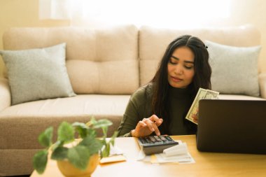 Aile bütçesi, vergiler ve tasarrufları hesaplayan, nakit, hesap makinesi ve dizüstü bilgisayarla kişisel finansmanı yöneten genç bir mali planlamacı