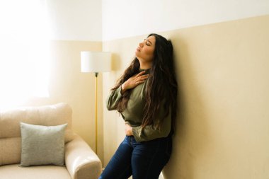 Karın ağrısı ve göğüs darlığı çeken bir kadın, evinde yalnız başına bir hastalık ya da stresten muzdarip.