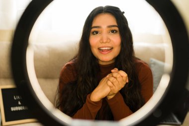 İçerik yaratan, kamerayla konuşan ve sosyal medya kanalı için halka ışığı ayarlı bir video kaydeden bir kadının portresi