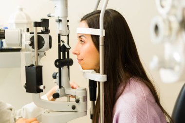 Optometri kliniğinde göz muayenesi yapılan bir hastanın profili. Profesyonel göz doktoru görüşü ve göz sağlığını kontrol ediyor.