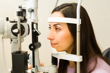 Optik klinikte göz testi yaptıran bir hasta. Doktor göz sağlığı kontrolü için göz muayenesi yapıyor.