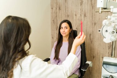 Kadın doktor, kadın hasta görüşünü inceliyor, görüş düzeltmesi için göz testi yapıyor ve bir sağlık merkezinde sağlık kontrolü yapıyor.