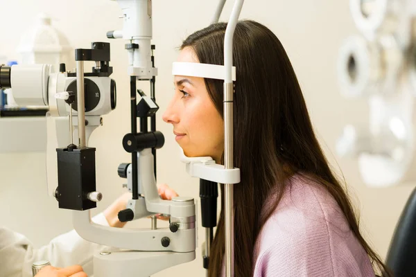 Optometri kliniğinde göz muayenesi yapılan bir hastanın profili. Profesyonel göz doktoru görüşü ve göz sağlığını kontrol ediyor.