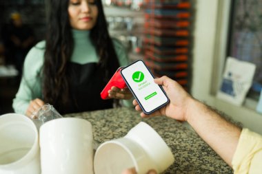 Müşteri akıllı bir telefon ve bir perakende mağazasında ödeme terminali ile başarılı bir ödeme işlemi yapıyor.