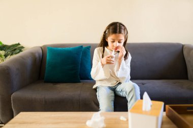 Sağlık sorunları yaşayan, evde kalan ve burun tıkanıklığını kanepede tedavi eden bir kız.