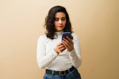 Akıllı telefon tutan, mesaj yazan ve internet içeriğine göz atan genç bir kadın. İletişim, teknoloji ve bağlantı yakalanıyor