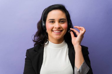 Çağrı merkezi ajanı olarak çalışan genç bir kadın, tele pazarlama yardımı teklif ediyor ve mikrofonunu ayarlarken gülümsüyor.