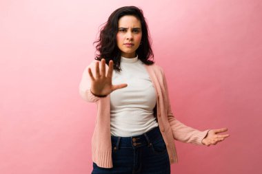 Kadın eliyle bir hareketi durduruyor. Reddetmeyi, reddedilmeyi ya da kişisel sınırlar koymayı öneriyor.