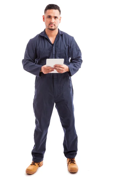 Homem vestindo macacão e usando um tablet — Fotografia de Stock