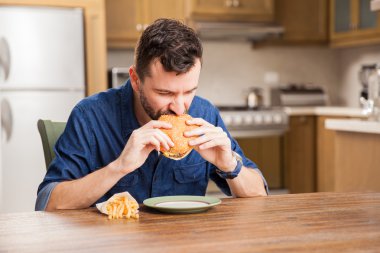 Bir hamburger ısırma sakallı adam