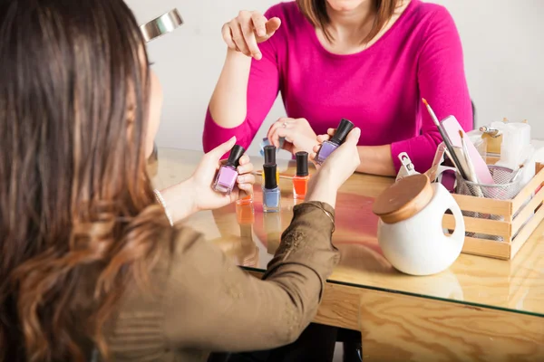 Brunette trying to choose nail polish — Stock Photo, Image