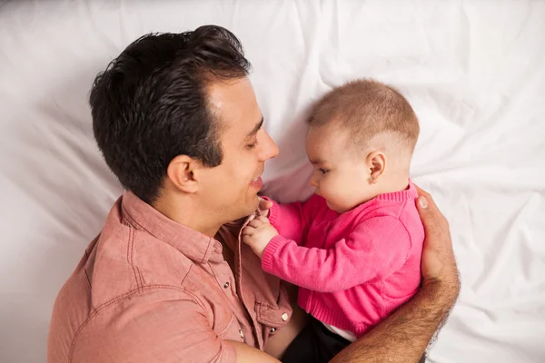 Father lying on a bed and spending some time with his baby — Stock Photo, Image