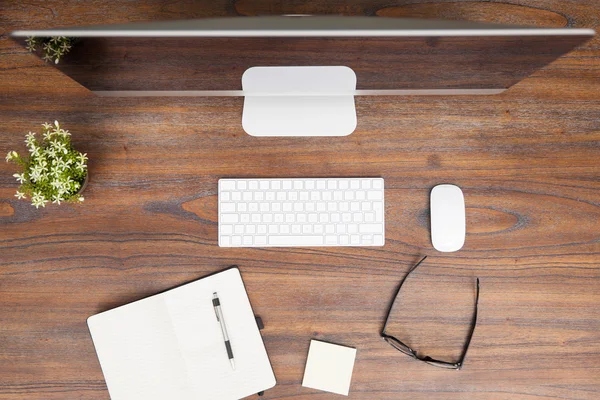 Computadora y un bloc de notas en un escritorio de madera — Foto de Stock