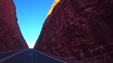 Araba, ABD 'deki parlak kırmızı dağlar boyunca yol boyunca sürer..