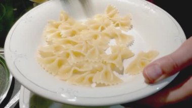 Kadın tabağa makarna koyuyor..