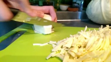 Kız kesme tahtasındaki bıçakla lahana kesiyor..