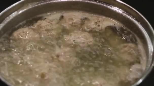 Garnek z gotującymi się klopsikami w wodzie w kuchni. — Wideo stockowe