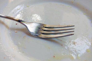 Yemekten sonra kirli beyaz tabakta bir çatal var.