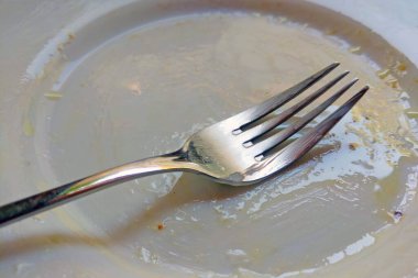 Yemekten sonra beyaz tabakta kirli bir çatal var.