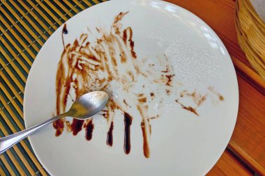 Tatlı yedikten sonra kaşıkla kirli beyaz tabak.