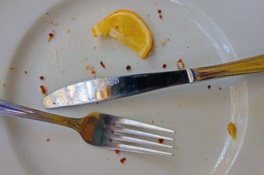 Yemekten sonra çatal ve bıçakla kirli bir tabağın üst görüntüsü.