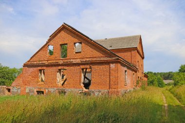 Kırsalda terk edilmiş eski bir kırmızı tuğla bina.