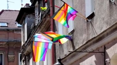 Evin binasında çok renkli Igbt bayrağı var. LGBT gay gurur bayrağı rüzgarda dalgalanıyor. Lezbiyen, gey, biseksüel, transseksüel, homoseksüel, gururlu sokak partisi kutlaması, odak dışı, film tahılları