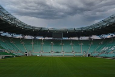 Wroclaw, Poland, August 22, 2021: empty modern stadium in Wroclaw before the rain. Overcast sky. Lack of people during the coronavirus epidemic. Ban on sporting events clipart